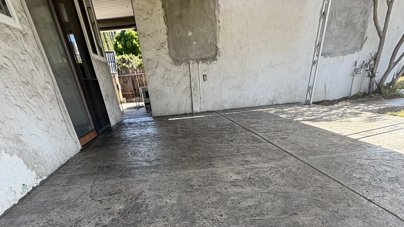 Stamped concrete patio under a covered back porch running out to the side yard at a stucco home