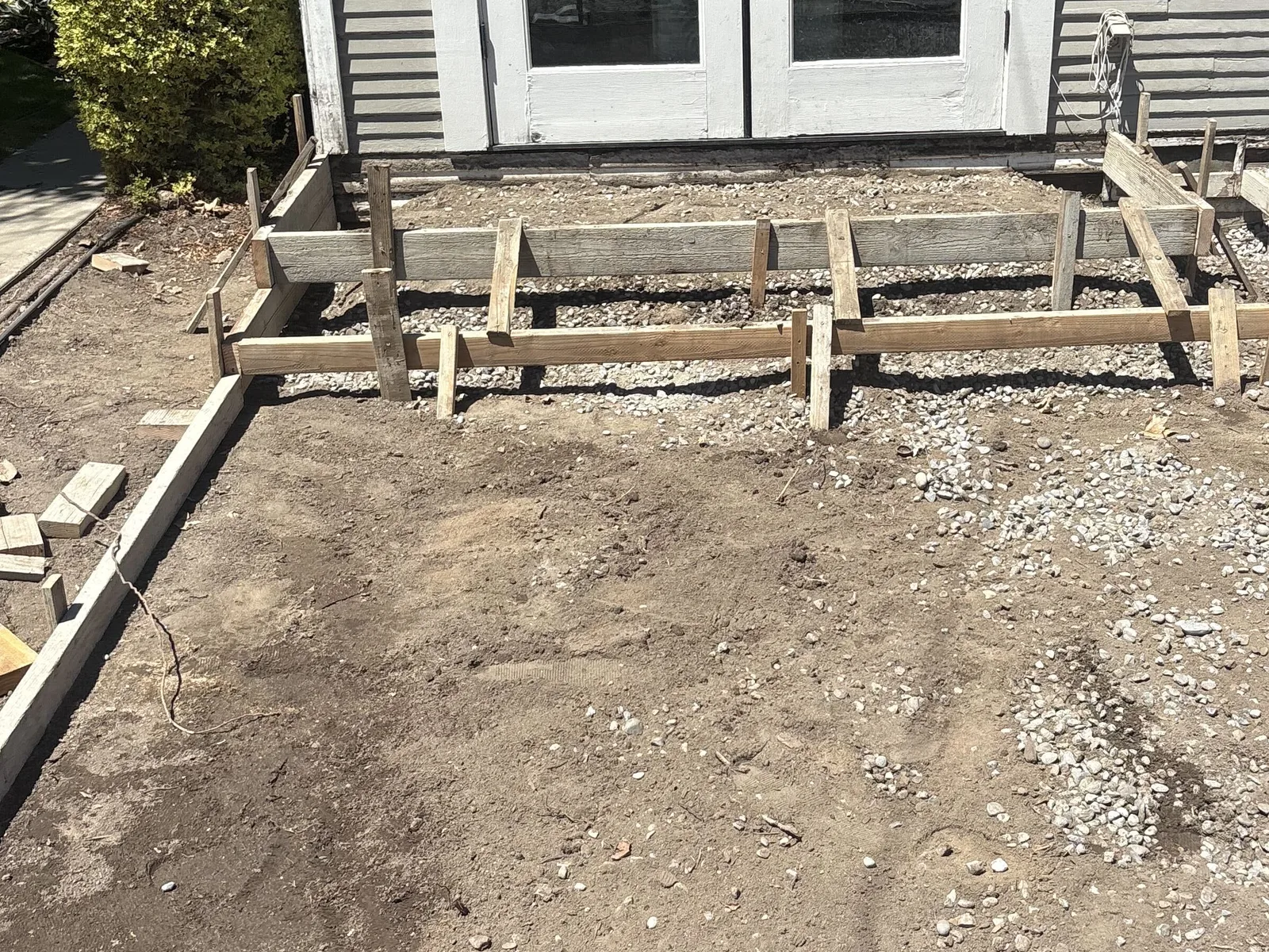 Wood forms and stakes set on a gravel base ready for a new concrete patio pour