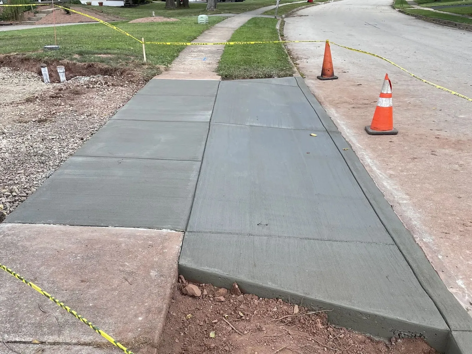 Finished concrete driveway approach and curb cut at the street, roped off with caution tape and cones