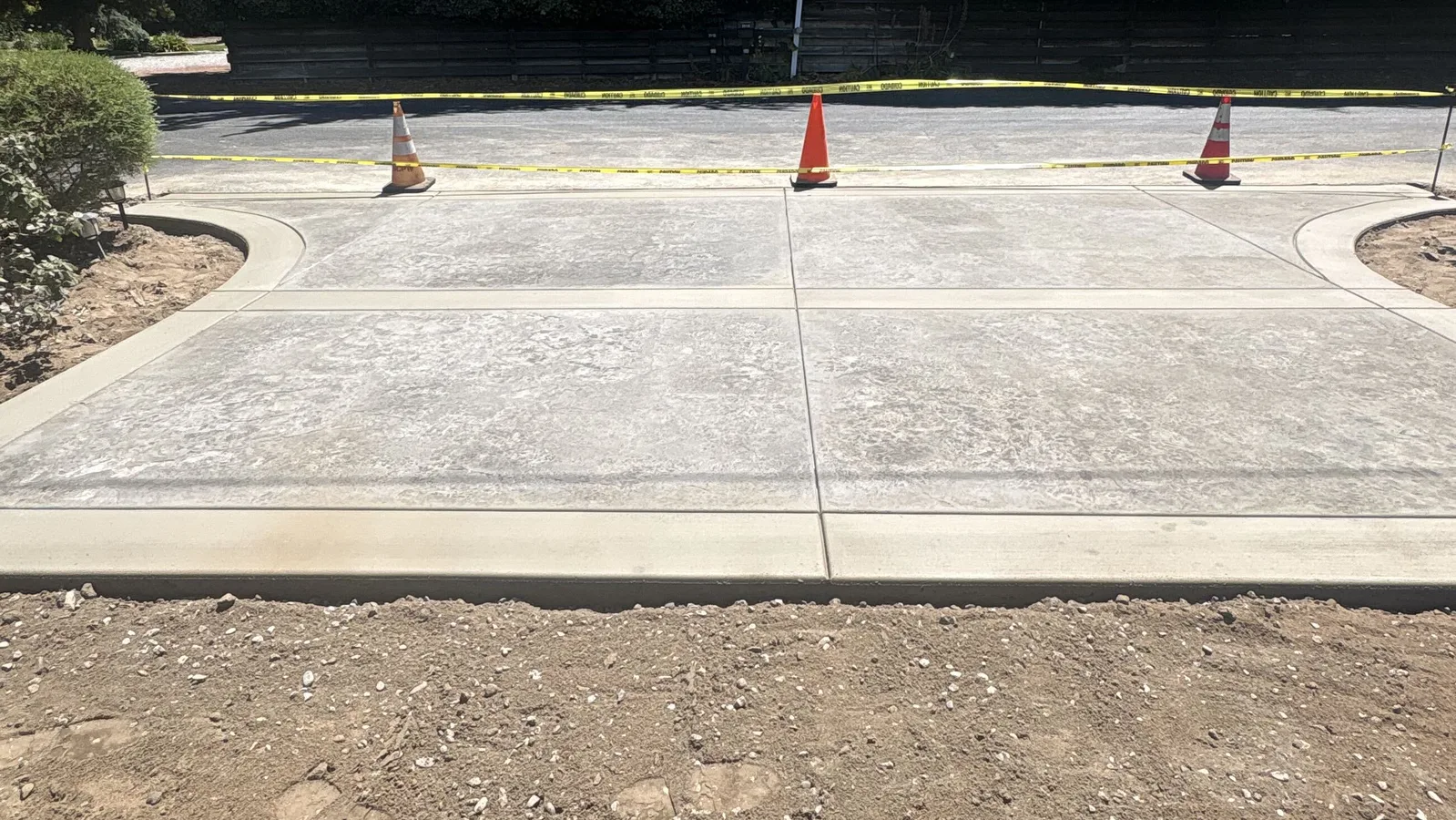 Finished concrete driveway pad roped off with caution tape and traffic cones at a Modesto-area home