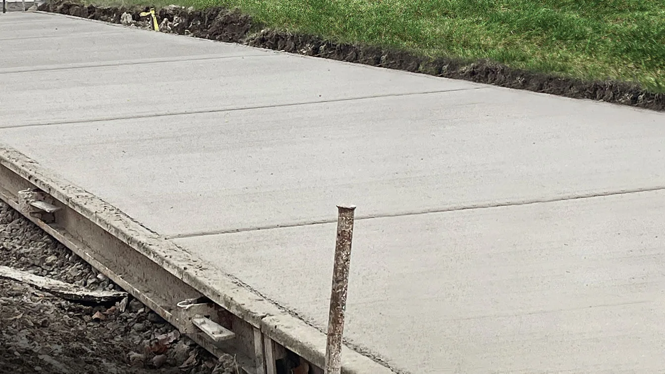 Freshly poured concrete sidewalk with the steel edge forms and stakes still in place