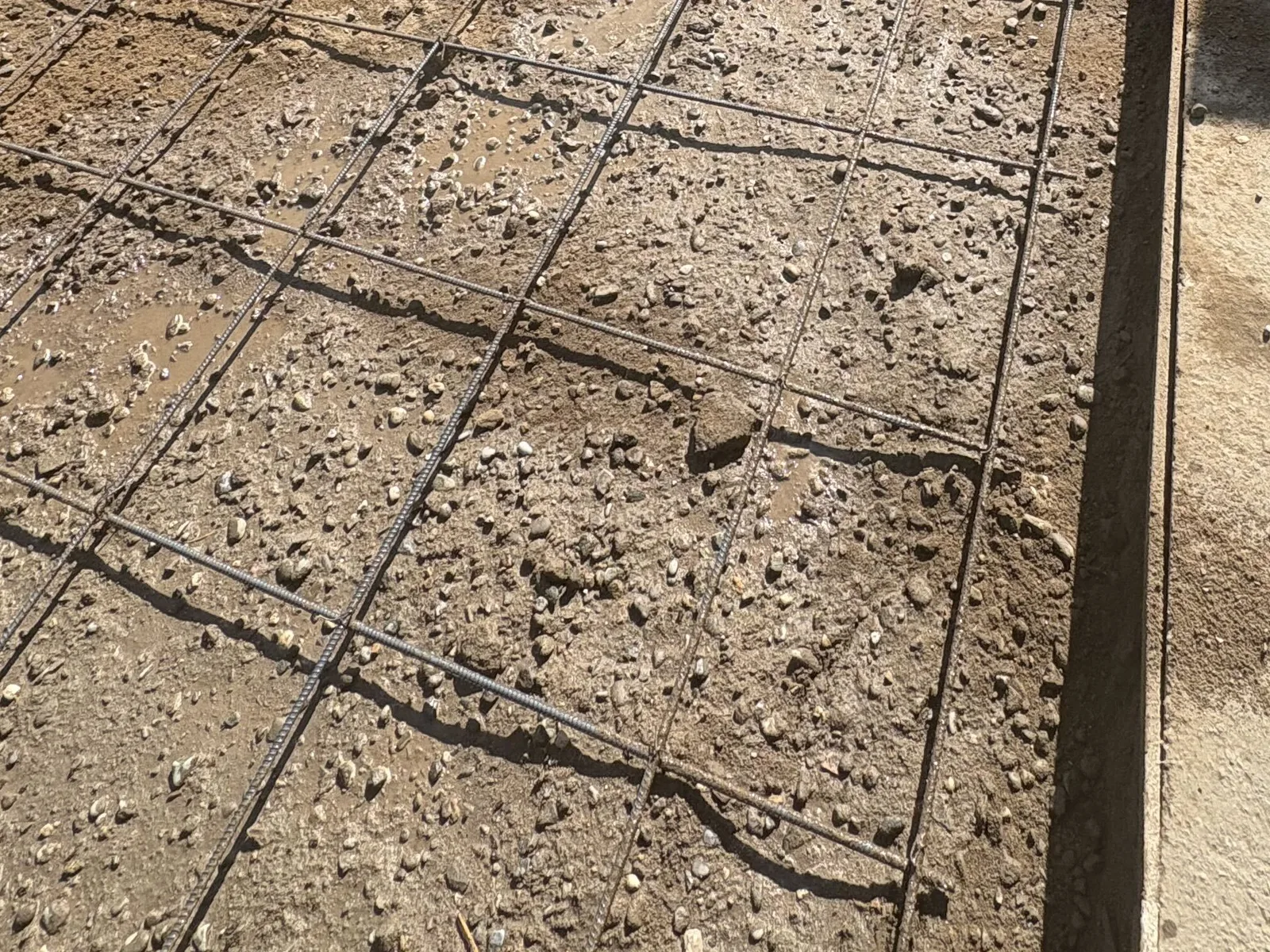 Close view of a tied rebar grid laid over gravel on a prepped concrete slab pad
