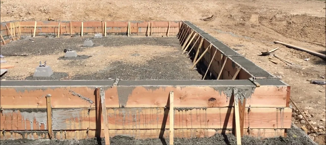 Poured concrete stem wall held in braced wood forms around a foundation footprint