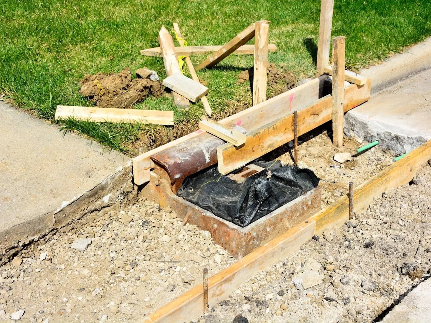 Wood and steel forms set for a concrete curb and gutter section beside an existing sidewalk