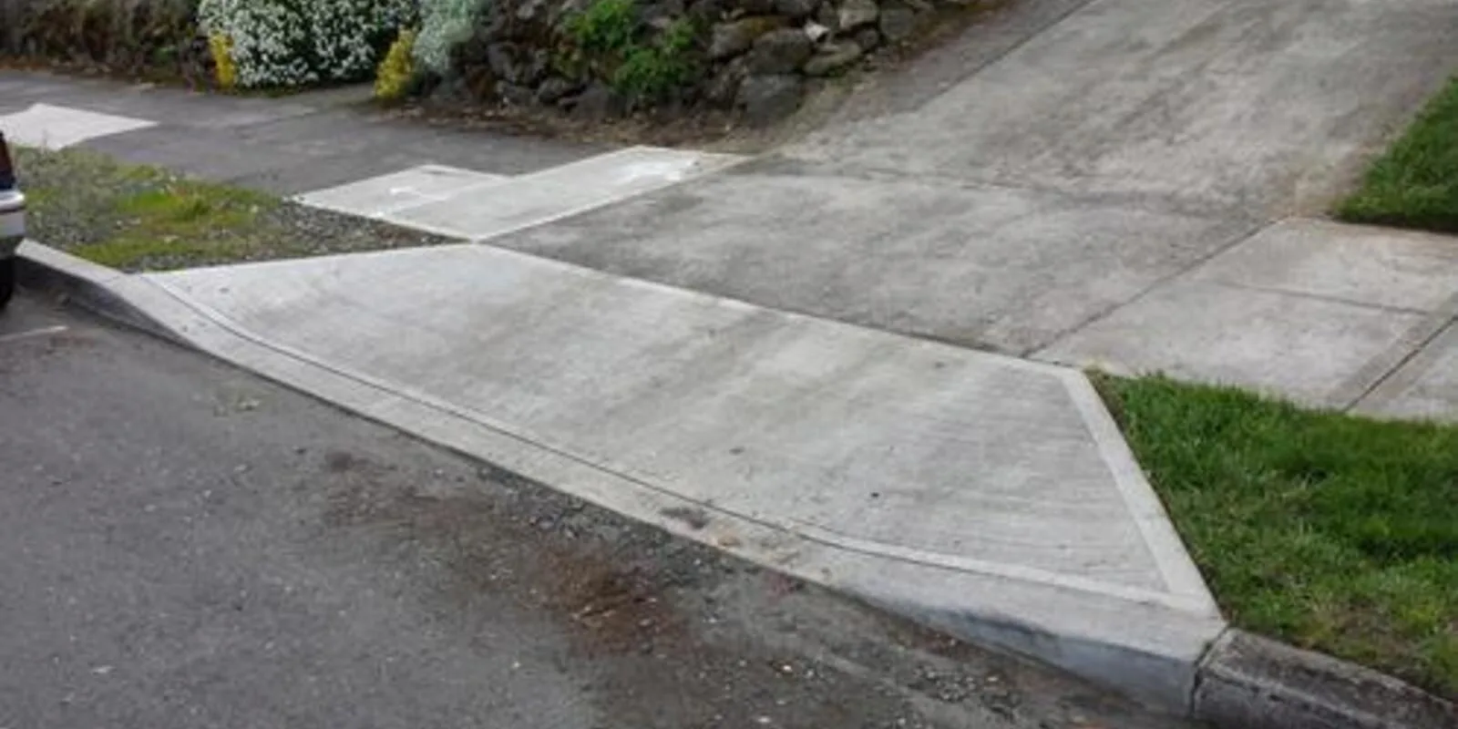 Finished concrete driveway approach with sloped curb wings where it crosses the public sidewalk