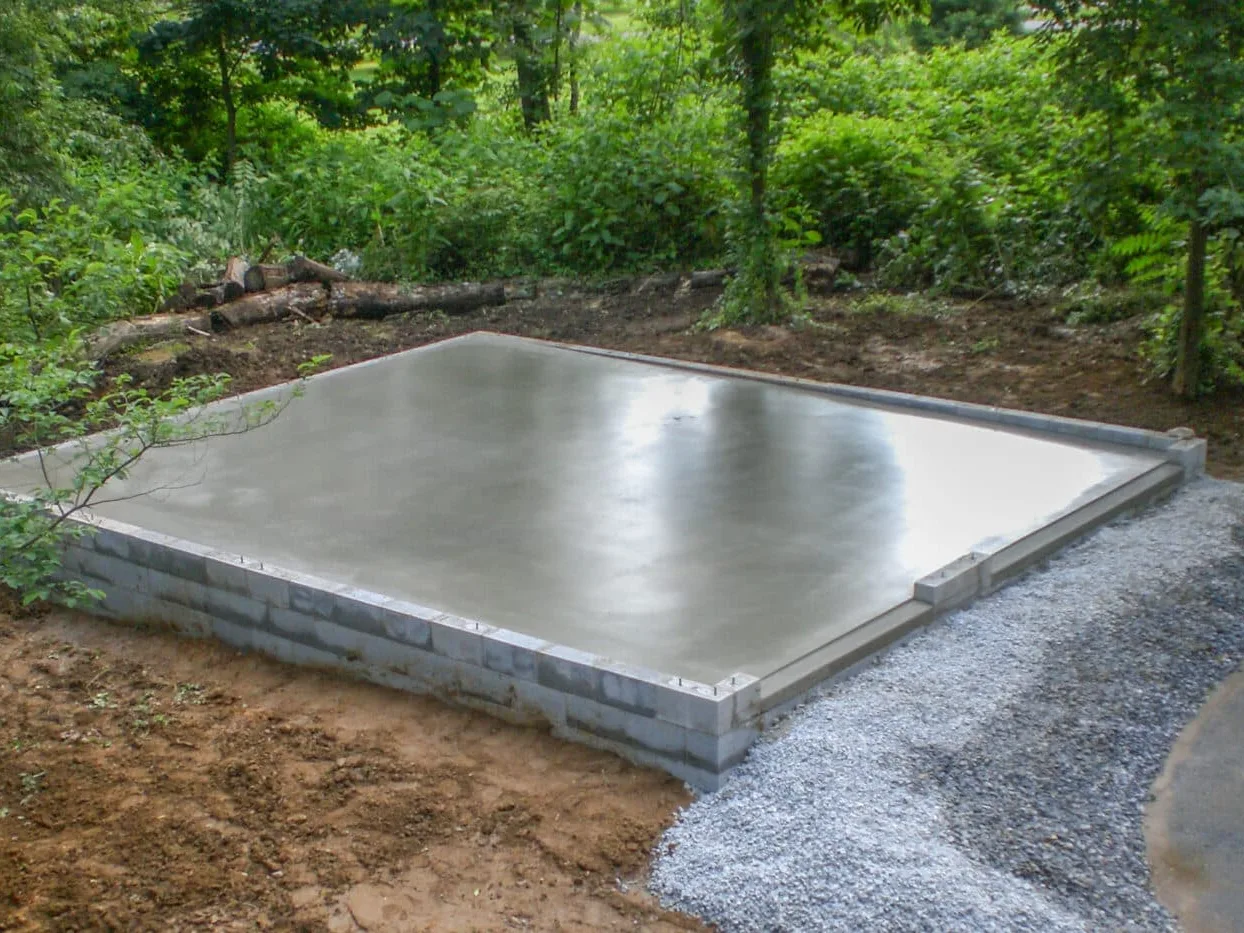 Finished concrete slab on a block stem wall, ready for a building, on a cleared wooded lot