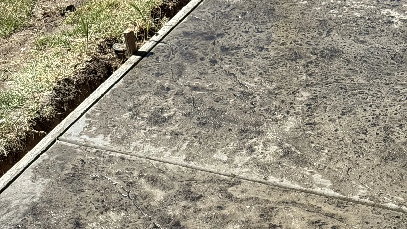 Stamped and textured concrete patio surface running alongside a strip of lawn at a Modesto-area home