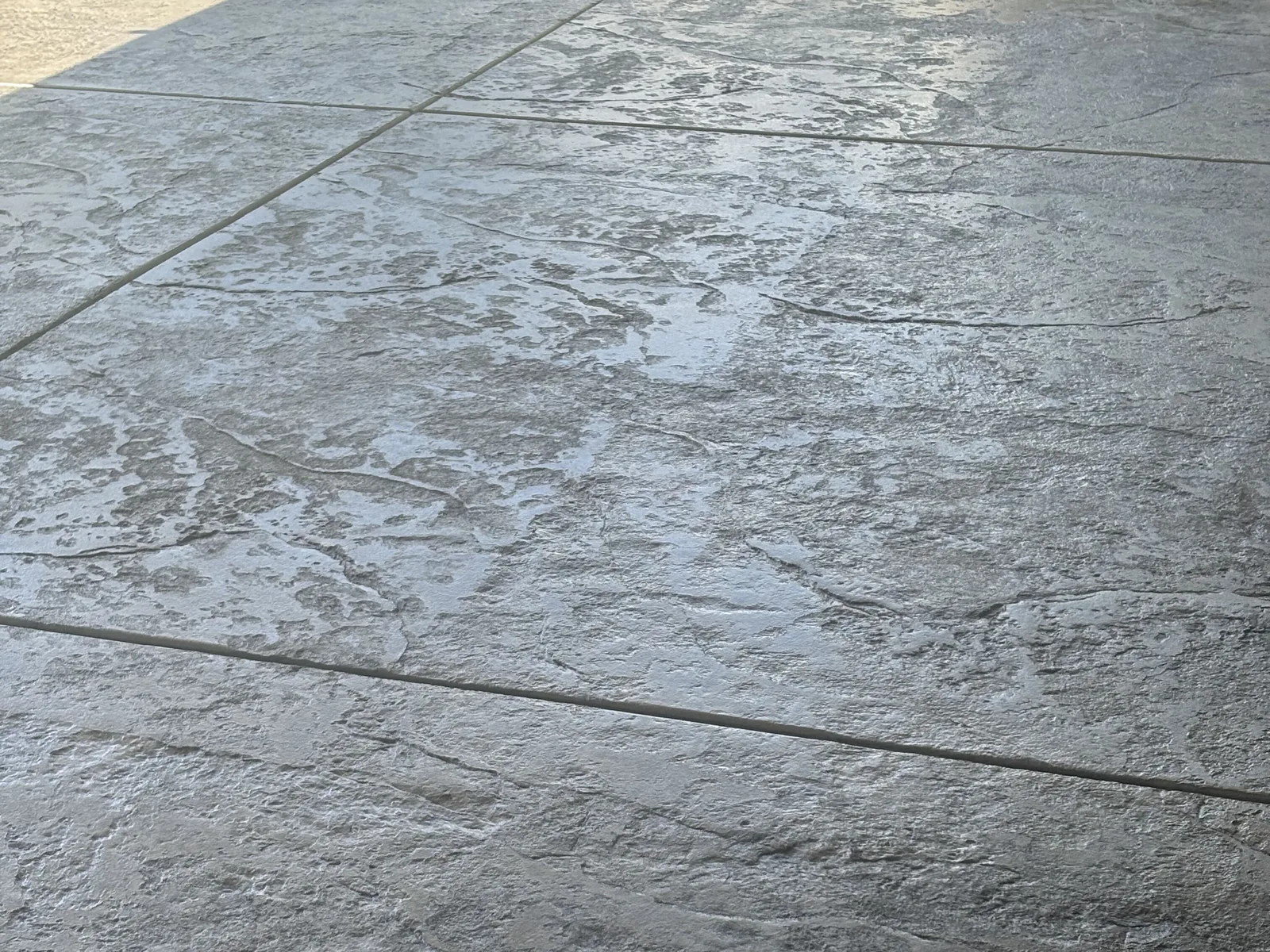 Close view of a freshly stamped concrete slab with a seamless stone texture and a tooled joint line